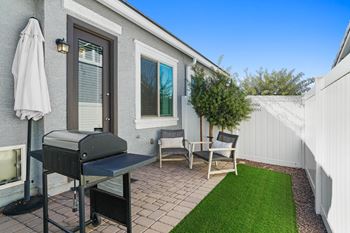 A backyard with a grill and chairs and a lawn